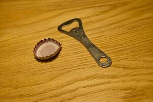 Bottle Opener and a Cap on Wooden Surface photo