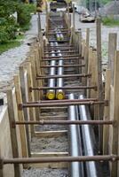 In the middle of a construction site lie the insulated metal pipes for district heating photo