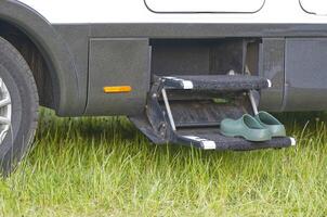 On some steps in front of the entrance of a camper there are green leisure garden shoes clogs photo