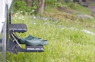 On the steps in front of the entrance of a camper there are green leisure garden shoes clogs in green photo