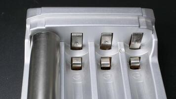 Close-up view of rechargeable batteries being inserted into a modern charger on a dark surface video