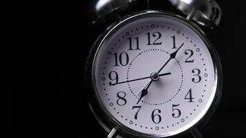 Close-up of Classic Analog Alarm Clock Showing Time in Dark Minimalist Setting with Reflective Surface video
