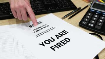Close-up of Hand Pointing at Termination of Employment Notice with 'You Are Fired' Text on Office Desk video