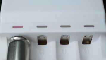 Close-up of AA batteries charging in a white battery charger with status indicators in home setting video