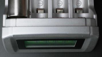 Close-up view of modern rechargeable batteries charging in a sleek electronic battery charger with digital display indoors video