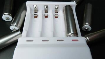 Close-up of Hand Inserting Rechargeable AA Battery into Modern White Charger on Black Surface video