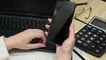 Person Holding Smartphone Displaying 'You Are Fired' Message in Modern Office Workspace with Laptop and Calculator video