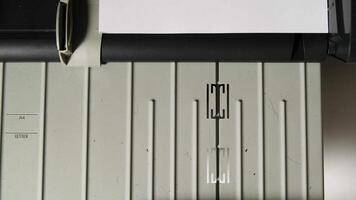 Close-up of hand feeding white paper into an office printer for smooth document printing process video