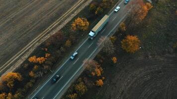 Aerial view of a truck driving in a flow of cars along the highway at sunset. video