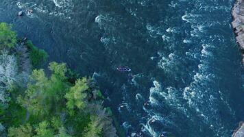 Aerial view of a kayak floating on a turbulent river between forest and stone cliffs. video