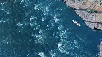 Aerial view of a kayak floating on a turbulent river between stone cliffs. video