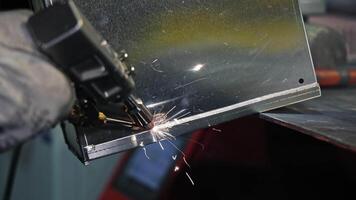 Manual welding process on metal edge, sparks fly during precision join, Skilled worker performs clean weld seam on industrial sheet metal corner video