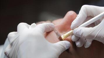 Augenbraue Microblading im ein Schönheit Salon, Kosmetikerin bewirbt sich Pigment mit Präzision Werkzeug, Nahansicht Aussicht von kosmetisch Augenbraue Erweiterung Prozess video