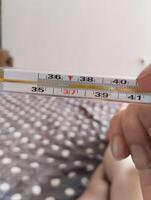 He holds a mercury thermometer in his hands with a high temperature. Illness malaise photo