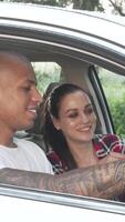 Joyful multiracial couple navigating their road trip with a smartphone in their car video