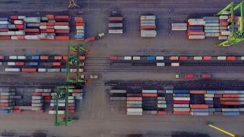 Aerial view of a busy container terminal with stacked containers, cranes, trucks, and railway tracks during cargo handling operations. video