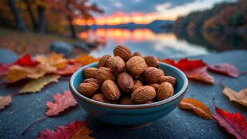 Bowl of Nuts with Fall Leaves and Scenic Lake Sunset photo