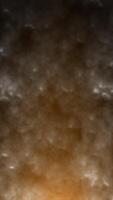 Dark textured surface with warm orange lighting gradient creating a smoky, cloud-like effect video