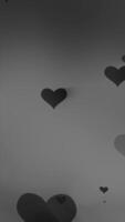 Floating dark hearts in soft monochrome tones on a smooth gradient background video