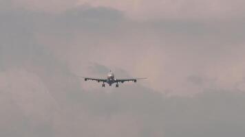Silhouette of an unknown plane approaching landing in a beautiful cloudy sunset sky, long shot, front view. Travel concept video