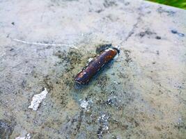 A rusty object sitting on a concrete surface photo