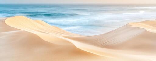 Serene beach landscape with gentle waves and soft sand dunes illuminated by the warm light of dawn. photo