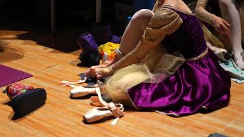 Ballerina in ornate costume adjusting pointe shoes on backstage floor video