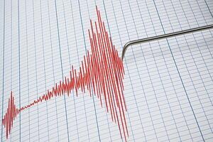 A seismograph records an earthquake by drawing red lines on paper to indicate strong tremors photo