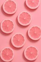 Abstract background, food art of pink lemon wedges sliced into circles on a pink background photo