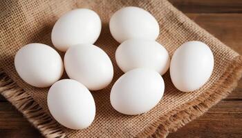 Fresh white chicken eggs on rye fabric, burlap on wooden brown surface in rustic interior. Rustic style, warmth and texture photo