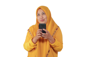 Southeast Asian woman in yellow hijab smiling and holding smartphone while daydreaming png