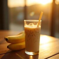 Banana Smoothie in Glass with Straw and Bananas on Table at Sunset photo