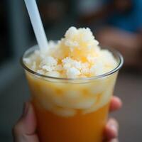 Holding Refreshing Shaved Ice Dessert with Straw in Clear Cup photo