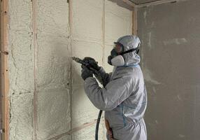 A construction worker applies foam insulation to a wall, creating an airtight seal. photo