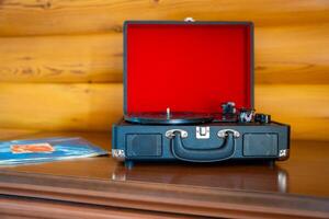 Open vintage record player in suitcase design with vinyl lying nearby. Retro music setup ready for playback in warm, nostalgic atmosphere. High quality photo