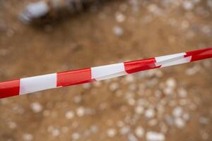 Red and white warning tape stretched across a restricted construction area. Symbol of safety measures, site control, and hazard prevention. High quality photo