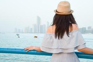 Against the stunning backdrop of Abu Dhabis skyline, a confident young woman dons a colorful turban, embodying the spirit of diversity and exclusivity that defines the UAE photo