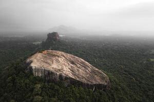 Aerial rising view visitors hiker on top viewpoint of Pidurangala Rock with Sigiriya rock view and the lush green jungle in Sri Lanka Cultural Triangle. photo