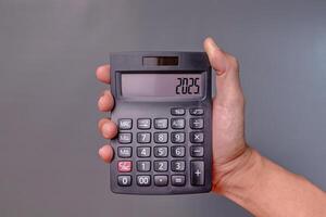 Hand holding a calculator with the number 2025 on the display photo