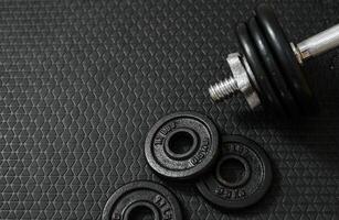 Iron dumbbells or weights on black floor with copy space for text on left photo