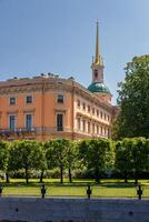 Mikhailovsky Castle, surrounded by well-maintained greenery and a fence, under a clear blue sky. photo