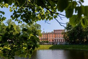 Mikhailovsky Castle in St. Petersburg, surrounded by trees, is visible across a pond in the park. photo