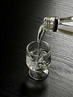 A bottle of vodka being poured into a glass photo