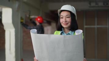 feliz multiétnico construtores equipe trabalhando construção desenvolvimento projeto construção sorridente ásia mulher inspetor agrimensor analisando projeto ao controle Construir caucasiano homem capacete de segurança uniforme engenheiro reparar video