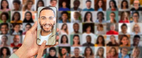 A person uses a smartphone to scan their face for identification purposes. In the background, there is a collage of various portraits showcasing diverse individuals. photo