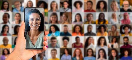 A hand holds a smartphone displaying a face scan while a collage of diverse individuals is visible in the background. This showcases the advancement in identification technology. photo