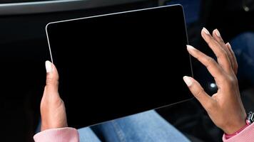 Modern remote work, online map, travel route in trip. Young african american lady holds tablet with empty screen in hands, surfing on internet and sits in car, cropped, pov, close up, free space photo