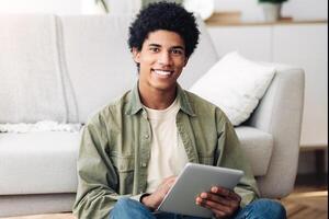 Web based learning. Positive black male student with tablet computer looking at camera and smiling at home, copy space. Happy teenager taking online degree program, attending web class photo