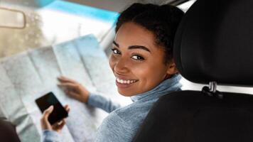 Find route, city transport and travel. Smiling attractive cute young african american woman driver researching map and holding phone with touch screen navigation map app with empty screen, copy space photo