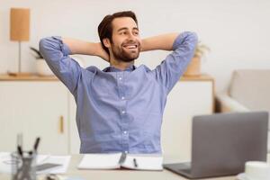 Successful Business Career. Relaxed Guy Holding Hands Behind Head Sitting At Laptop At Workplace In Modern Office, Happy With His Life And Job. Carefree Businessman Concept photo